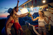 © luckybusiness - Friends enjoying summer evening in front of camper rv. Toasting with beer and dancing. Travel, holiday, weekend, togetherness, lifestyle concept.