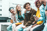 Fototapeta Londyn - Happy multiracial friends talking and laughing together hanging in city street - Multicultural university students having fun in college campus - Life style concept with guys and girls smiling outside