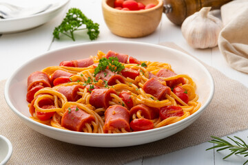 Hot dog or sausage stuffed with spaghetti in tomato sauce in white plate