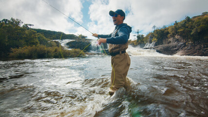 Fly fishing. Fisherman in waders fishing on the rapid river