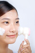 © Marc Tran/Stocksy - Young woman washing face with brush and cleansing foam on face