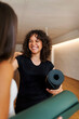 © Valentina Barreto/Stocksy - Women holding mat in yoga studio