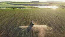 Aerial View Of Working Farming Tractor Spraying On Field With Sprayer Water Or Herbicides And Pesticides Against Diseases And Insects. Nature Landscape Of Rivers, Reservoirs. Agricultural Industry.