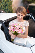 © Manu Prats/Stocksy - Bride in wedding car holding bridal bouquet