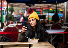 Woman Using Smartphone At Restaurant Terrace