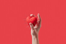 Red Heart With Metal Spikes Held By Female Hand.