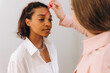 © Alina Hvostikova/Stocksy - Crop beautician plucking eyebrows with tweezers