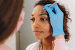 © Alina Hvostikova/Stocksy - Crop beautician plucking eyebrows with tweezers