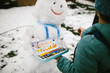 © Maria Manco/Stocksy - Girl uses paint to decorate snowman