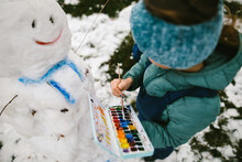 Girl Uses Paint To Decorate Snowman