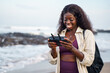 © Jovo Jovanovic/Stocksy - Woman holding a wireless remote control of a drone at the beach