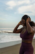 © Jovo Jovanovic/Stocksy - Woman wearing headphones standing at the beach