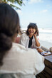 © Jovo Jovanovic/Stocksy - Two women talking and laughing at the beach shore