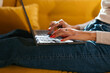 © BONNINSTUDIO/Stocksy - Crop woman typing on laptop on sofa