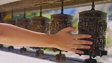 Close Up Of Woman's Hand Touching And Spinning Prayer Wheels In Slow Motion As The Camera Follows, Nepal