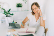 © Olga Moreira/Stocksy - Woman talking on phone while working in her home office