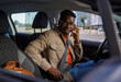 © Jovo Jovanovic/Stocksy - Young man fastening car seatbelt while talking on mobile phone