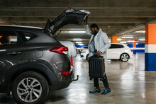Black Businessman With Suitcase Near Car In Parking