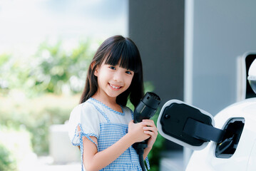 A playful girl holding an EV plug, a home charging station providing a sustainable power source for electric vehicles. Alternative energy for progressive lifestyle.