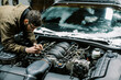 © Serena Burroughs/Stocksy - Millennial Mechanic working in engine bay of a car