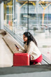 © David Prado/Stocksy - Woman with suitcase using cellphone in airport