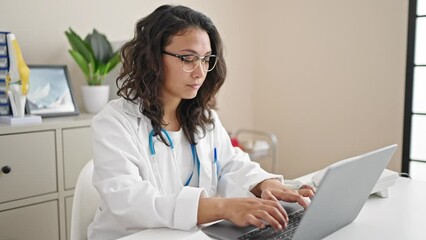 Canvas Print - Young beautiful hispanic woman doctor using laptop working at clinic