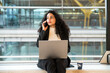 © David Prado/Stocksy - Businesswoman using gadgets in modern airport
