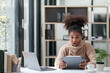 © Treerat - American African Woman working in the office with computer phone and Tablet.
