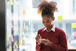 © Treerat - African American female employee write down on colorful sticky notes manage list, concentrated biracial woman work on startup brainstorm collaborate plan on stickers on glass wall