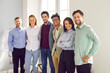 © Studio Romantic - Portrait of happy diverse colleagues looking at camera. Team of cheerful successful employees in formal wear posing together in modern office. Teamwork, cooperation, partnership