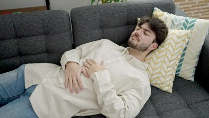 Sticker - Young hispanic man suffering for stomach ache lying on sofa at home