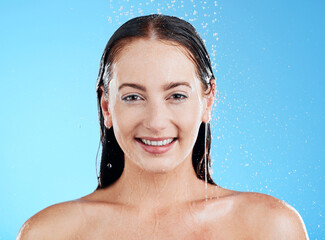 Shower, water and portrait of a happy woman in a studio from cleaning and skincare. Wellness, cosmetics and beauty routine of a female model with dermatology and self care with blue background