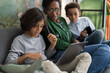 © Studio Marmellata/Stocksy - Black mother sitting with sons using gadgets