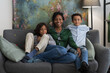© Studio Marmellata/Stocksy - Happy black woman on couch with sons