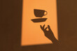 © Marcos Osorio/Stocksy - Shadow of a hand throwing a cup of coffee into the air