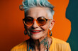 © alexkoral - stylish elderly happy woman in tattoos in sunglasses smiles on a bright background. Generative AI