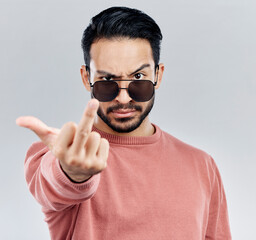 Wall Mural - Hand, middle finger and portrait of man in studio with sunglasses, attitude and gesture against grey background. Face, rebel and emoji by asian male edgy, expression and personality while isolated