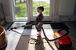 © Cara Dolan/Stocksy - Helpful Toddler Standing in Entryway Vacuuming Rug