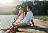 Love, laugh and pier with couple at lake for bonding, romance and affectionate date. Nature, travel and holiday with man and woman sitting on boardwalk in countryside for happy, summer and vacation