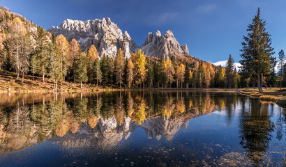 Aufkleber -  Inckedible autumn scenery with reflections. Amazing autumn landscape in the mountains with yellow larches and lake glowing by sun and high mountain peaks behind. Antorno lake. Picture of Wild area.