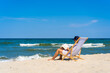 © Jacek Chabraszewski - Woman relaxing on beach reading book sitting on sunbed