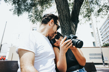 Photograph of a couple looking at photos on a reflex camera. Lifestyle concept and people.