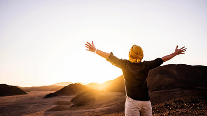 Wall Mural - Happy man with arms outstretched standing on the top of the mountain enjoying sunset - Successful traveler with hands up celebrating victory outside - Travel, healthy lifestyle and winning concept