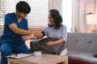 A health visitor is measuring blood pressure a sick elderly woman who is sitting on a sofa at home. This scene illustrates the concept of home health care services.