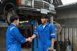 © Natee Meepian - Two Asian automotive mechanic repairman handshake in garage. Vehicle service manager working in mechanics workshop, feel happy and success after check and maintenance car engine for customer.