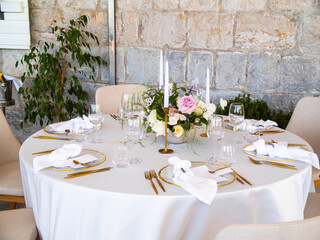 Wall Mural - Wedding banquet concept. Chairs and round table for guests, served with cutler and, flowers and crockery and covered with a tablecloth