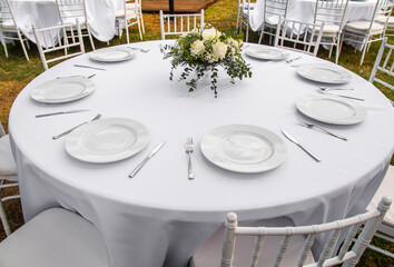 Wall Mural - Beautiful outdoor wedding decoration in city. Candles and dried flowers and accessories with bouquets and glasses on table with linen tablecloth on newlywed table on green lawn