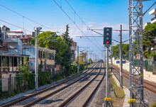 Railway tracks in the city on blue sky background. Train station, traffic light shows red signal on railway, stop light