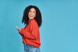 Young curious smiling happy pretty latin woman holding mobile phone, doing online shopping on cell, using apps on cellphone looking aside at copy space standing isolated on blue background.
