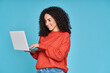 © insta_photos - Young latin woman student using laptop device standing isolated on blue background. Smiling female model user holding computer, typing, surfing, searching job online or shopping website.